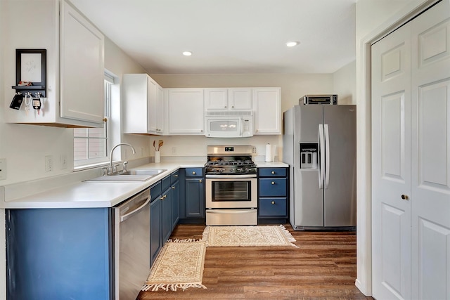 kitchen with a sink, light countertops, wood finished floors, stainless steel appliances, and blue cabinetry