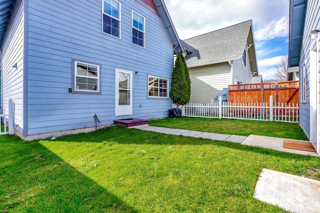 rear view of house with a yard and fence