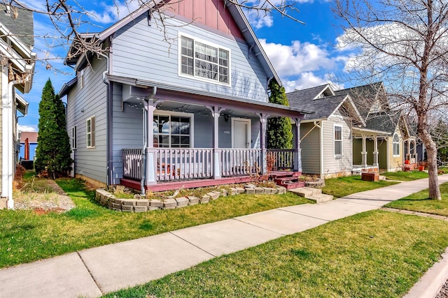 view of front of property featuring board and batten siding, a front lawn, and covered porch