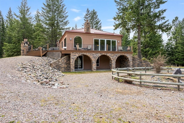 1636 Lake Blaine Rd, Kalispell, MT 59901 - view of front facade with stone siding, a chimney, stucco siding, a wooden deck, and gravel driveway