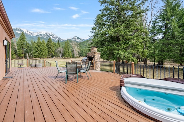1636 Lake Blaine Rd, Kalispell, MT 59901 - wooden terrace with an outdoor stone fireplace, a mountain view, a covered hot tub, and outdoor dining space