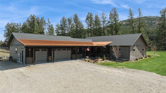 124 Hidden Waters Ln, Kalispell, MT 59901 - view of front of home with an attached garage, a front lawn, dirt driveway, stone siding, and a mountain view