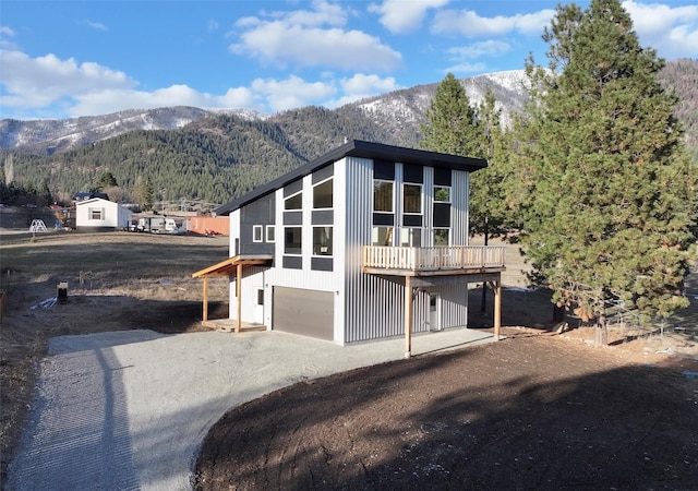 519 Grizzly Dr, Thompson Falls, MT 59873 - back of house featuring an attached garage, board and batten siding, a deck with mountain view, and driveway