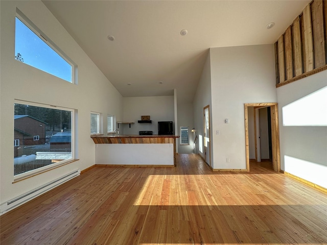 519 Grizzly Dr, Thompson Falls, MT 59873 - unfurnished living room with baseboard heating, wood finished floors, high vaulted ceiling, and plenty of natural light