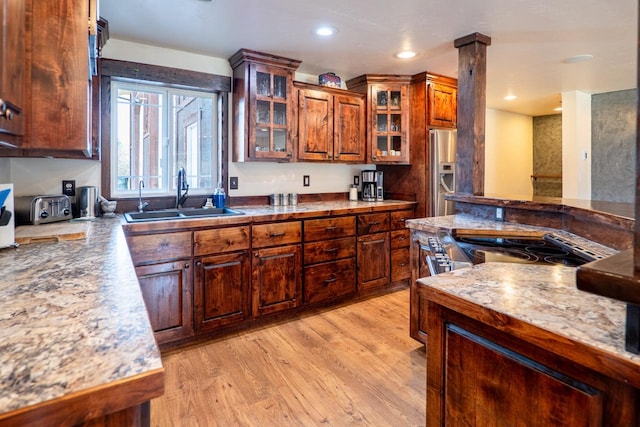 kitchen with stainless steel fridge with ice dispenser, recessed lighting, glass insert cabinets, light wood-style floors, and a sink
