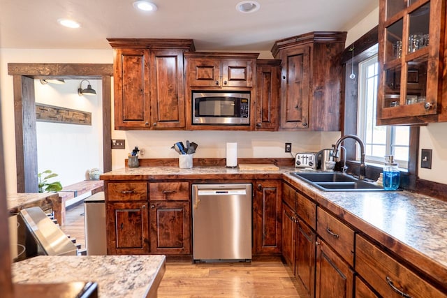 kitchen with glass insert cabinets, light wood-style flooring, recessed lighting, appliances with stainless steel finishes, and a sink