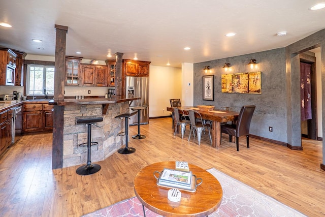 dining room featuring light wood-style flooring, decorative columns, baseboards, and recessed lighting