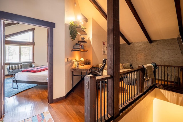 hallway featuring baseboards, vaulted ceiling with beams, and wood finished floors