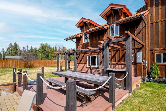 wooden deck featuring outdoor dining space, a pergola, fence, and a lawn