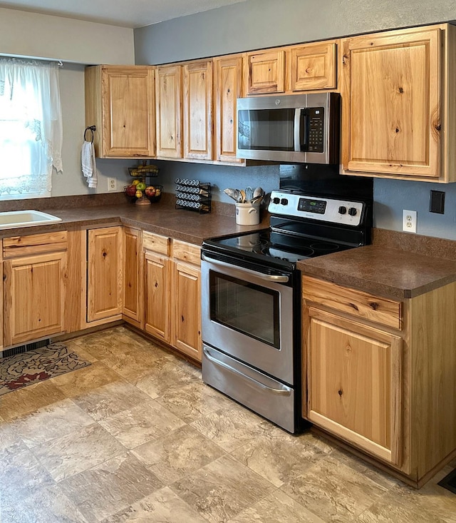 kitchen featuring visible vents, a sink, appliances with stainless steel finishes, dark countertops, and stone finish flooring