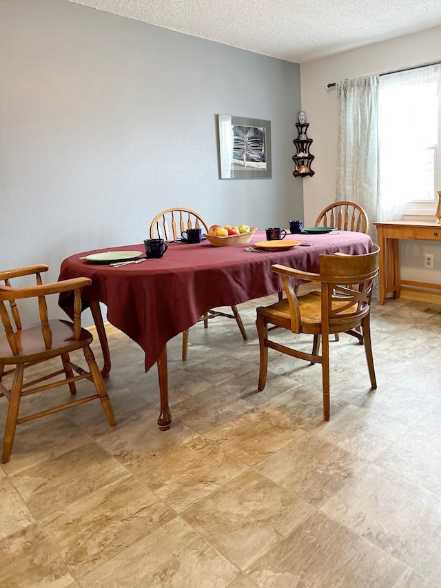 dining area featuring light floors and a textured ceiling