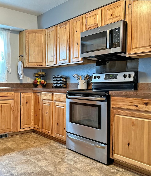 kitchen featuring dark countertops, visible vents, appliances with stainless steel finishes, and stone finish floor
