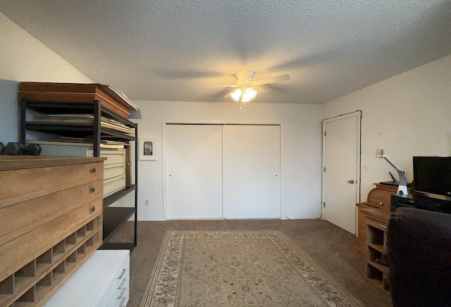 carpeted bedroom with a closet, a textured ceiling, and a ceiling fan