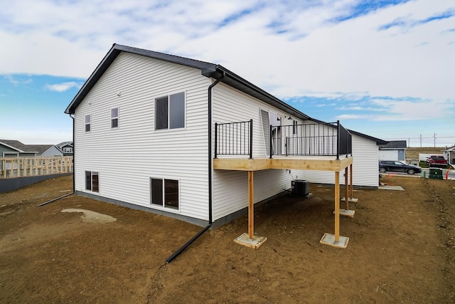 view of property exterior with central AC, fence, and a deck