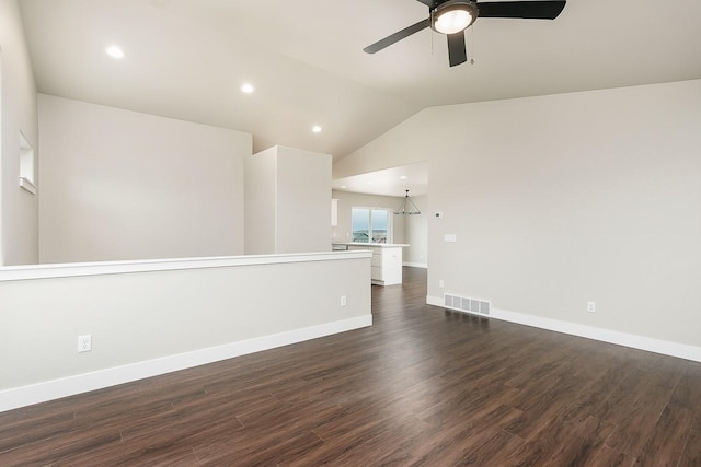 empty room featuring baseboards, vaulted ceiling, visible vents, dark wood finished floors, and ceiling fan