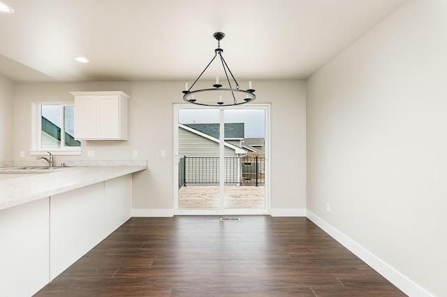unfurnished dining area with dark wood-type flooring, a sink, baseboards, and recessed lighting