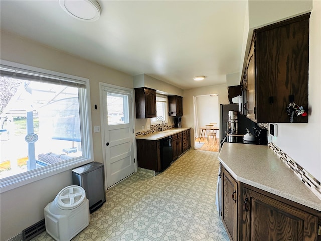 767 33rd Ave NE, Great Falls, MT 59404 - kitchen with black dishwasher, dark brown cabinets, light countertops, freestanding refrigerator, and light flooring