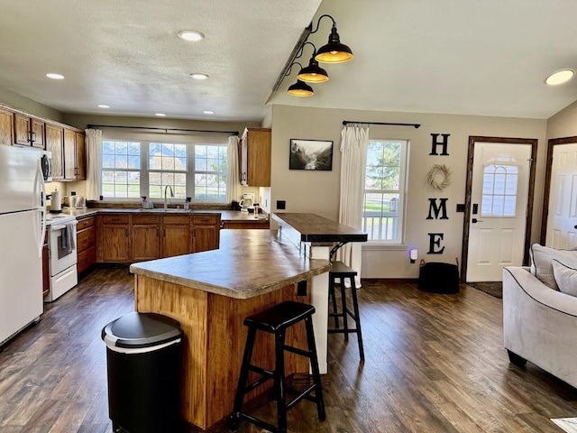992 Trumble Creek Rd, Kalispell, MT 59901 - kitchen with white appliances, brown cabinets, a breakfast bar, dark wood-style flooring, and recessed lighting