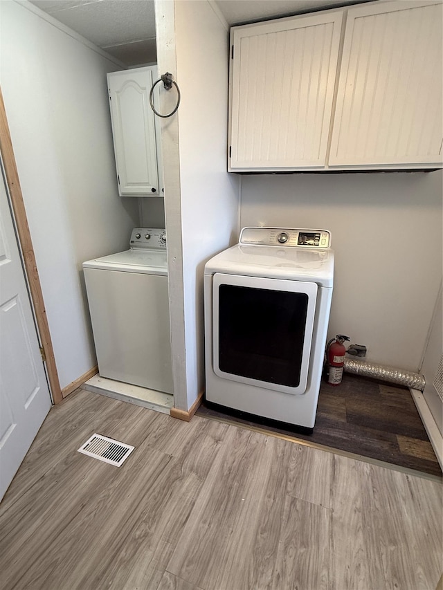 3805 7th St NE Unit 26, Great Falls, MT 59404 - clothes washing area with light wood-style flooring, visible vents, baseboards, cabinet space, and washer and clothes dryer