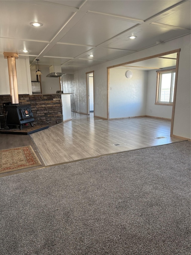 3805 7th St NE Unit 26, Great Falls, MT 59404 - unfurnished living room featuring baseboards, a wood stove, carpet, wood finished floors, and coffered ceiling