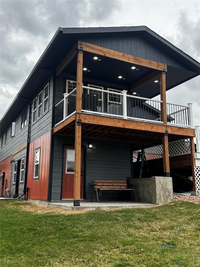 back of property with a deck and a lawn