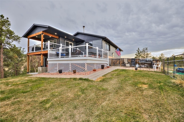 back of property with a wooden deck, fence, and a lawn