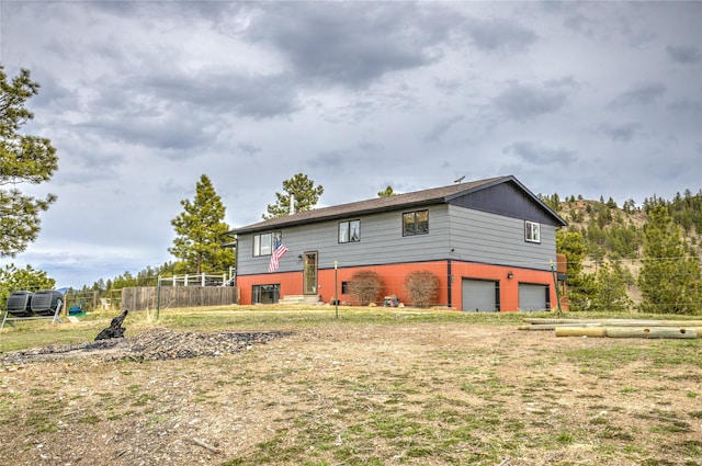 rear view of property featuring a garage and fence