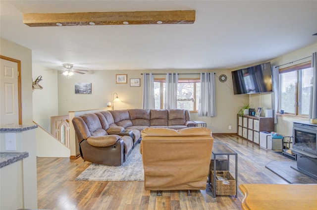 living room featuring wood finished floors, a wood stove, and ceiling fan