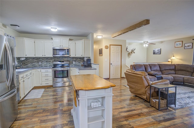 kitchen featuring open floor plan, backsplash, white cabinetry, and stainless steel appliances