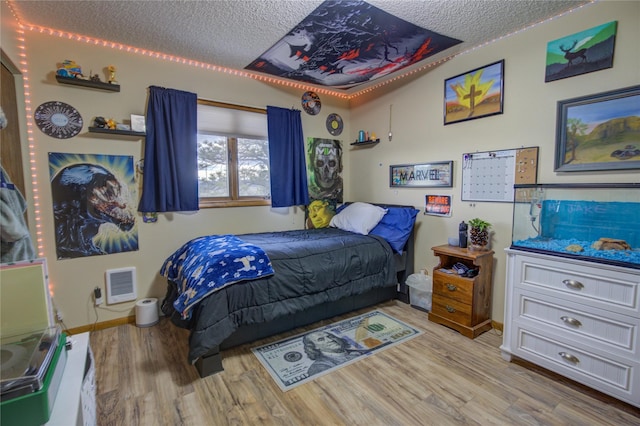 bedroom with a textured ceiling, wood finished floors, and baseboards