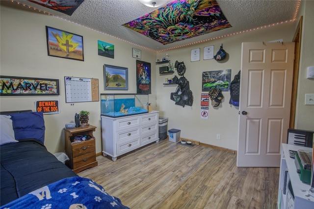bedroom featuring light wood-style flooring, a textured ceiling, and baseboards