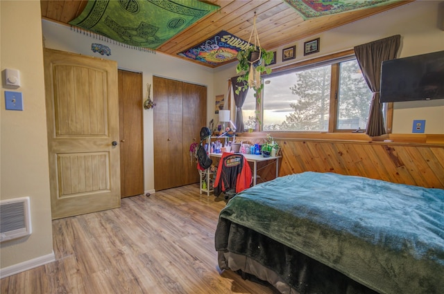 bedroom with baseboards, visible vents, multiple closets, wood ceiling, and wood finished floors