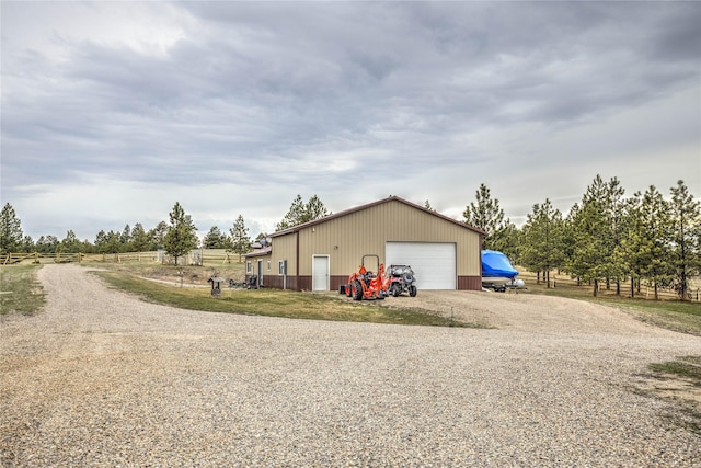 view of home's exterior featuring a garage, driveway, fence, and an outbuilding