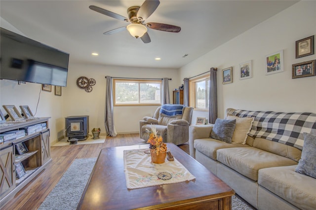 living area with baseboards, recessed lighting, a wood stove, ceiling fan, and wood finished floors
