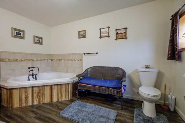 full bath with a bath, toilet, wood finished floors, and baseboards