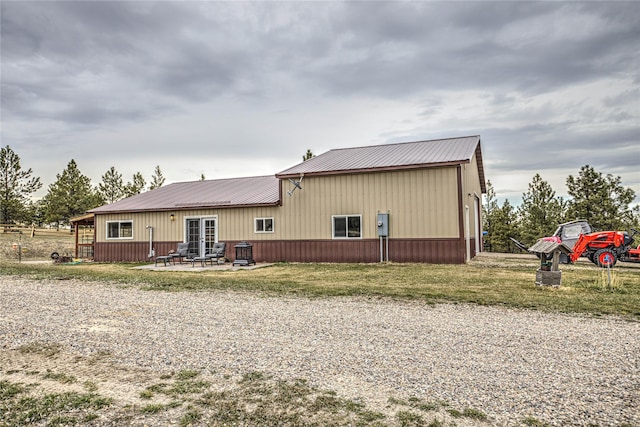rear view of house with a yard, metal roof, and a patio area