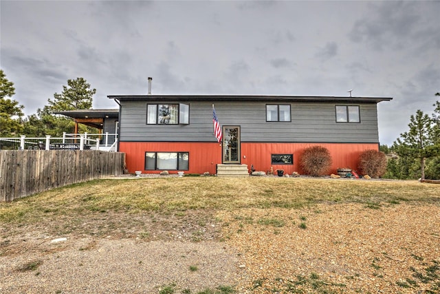 raised ranch with a front yard, entry steps, and fence