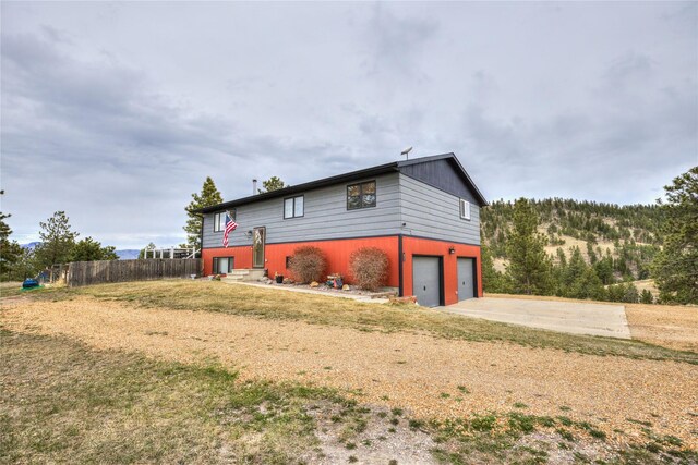 view of side of property with an attached garage, concrete driveway, and fence