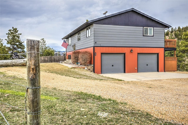view of side of home with an attached garage, a lawn, fence, and dirt driveway