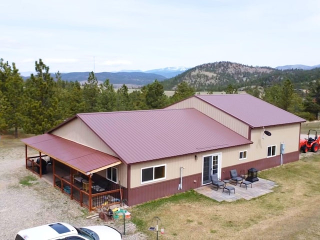 back of property with a mountain view, a lawn, a patio, and metal roof