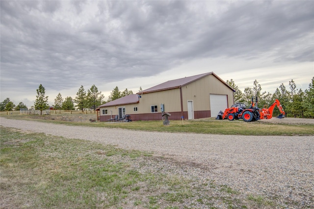 exterior space with an outbuilding, a yard, a detached garage, metal roof, and driveway