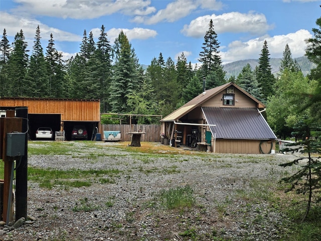 64 Ponderosa Ln, Thompson Falls, MT 59873 - view of front of house with an outbuilding, a metal roof, a mountain view, an outdoor structure, and a view of trees