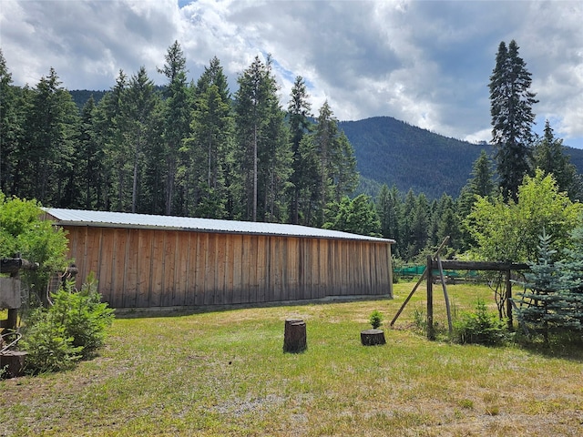 64 Ponderosa Ln, Thompson Falls, MT 59873 - view of grassy yard featuring a wooded view, an outbuilding, and a mountain view
