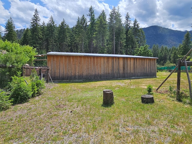 64 Ponderosa Ln, Thompson Falls, MT 59873 - view of green lawn featuring a mountain view, a view of trees, a pole building, and an outbuilding