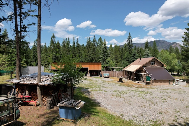64 Ponderosa Ln, Thompson Falls, MT 59873 - rear view of house with a metal roof, a mountain view, an outdoor structure, and a forest view