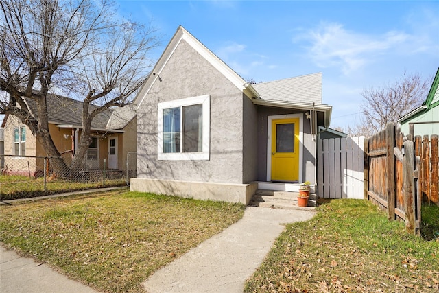 view of front of house featuring roof with shingles, stucco siding, fence, and a front lawn