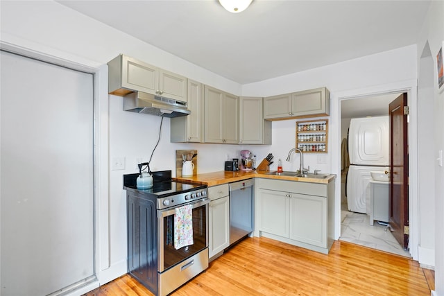 kitchen featuring a sink, appliances with stainless steel finishes, stacked washer and clothes dryer, under cabinet range hood, and gray cabinets