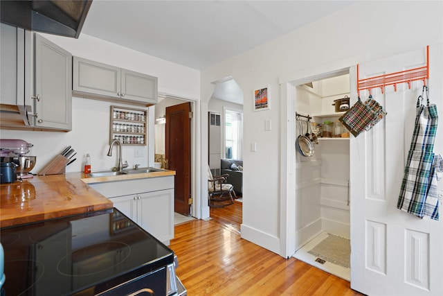 kitchen featuring light wood-style floors, electric range, a sink, and wooden counters