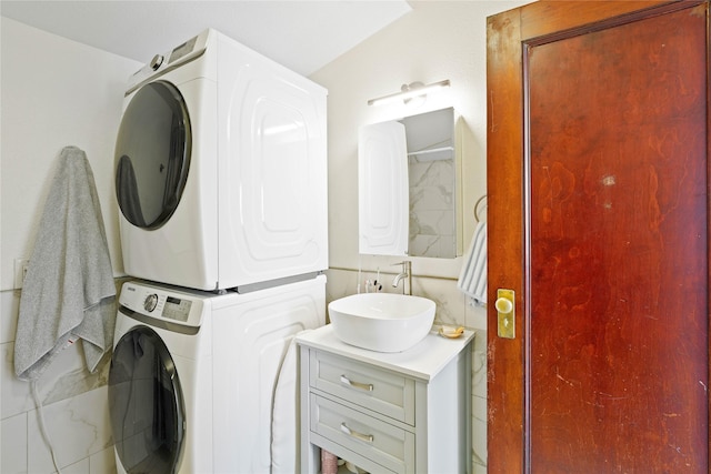 washroom featuring laundry area, a sink, and stacked washer / drying machine