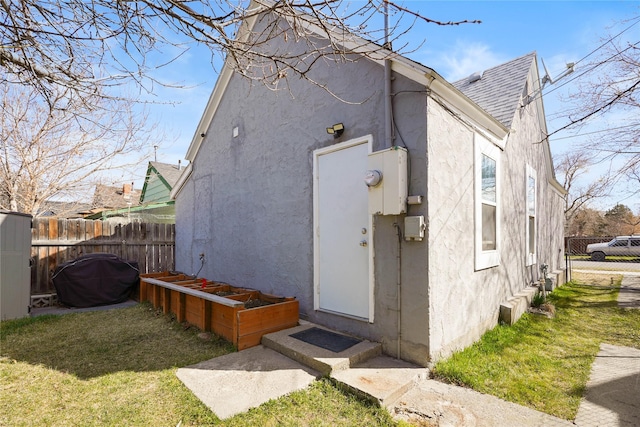 back of house featuring fence, a shingled roof, and stucco siding